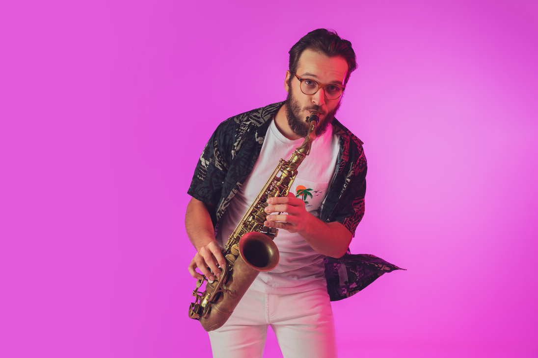 Young caucasian jazz musician playing the saxophone in neon light
