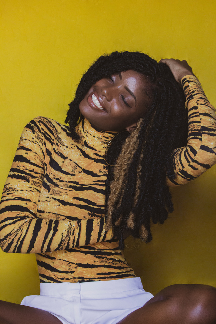 Portrait of a Smiling Woman in Dreadlocks on Yellow Background