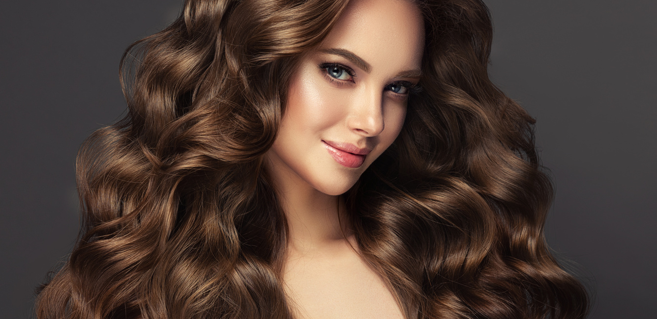 Young, brown haired beautiful model with long,  curly, well groomed hair. Excellent hair waves. Hairdressing art and hair care.